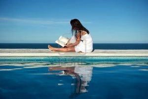 big_7219763-mujer-leyendo-un-libro-en-la-pared-de-una-piscina-con-vista-al-mar-en-arraial-d-ajuda-bahia-brasil
